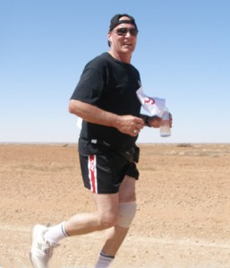 Steve Baines, Coober Pedy's Mayor jaunts along with Coober Pedy now visible and team mates well behind