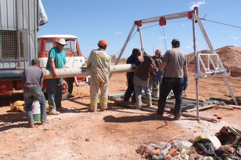 On the third day police and volunteers lower heavy pipes into a mine shaft for suction of debris. 